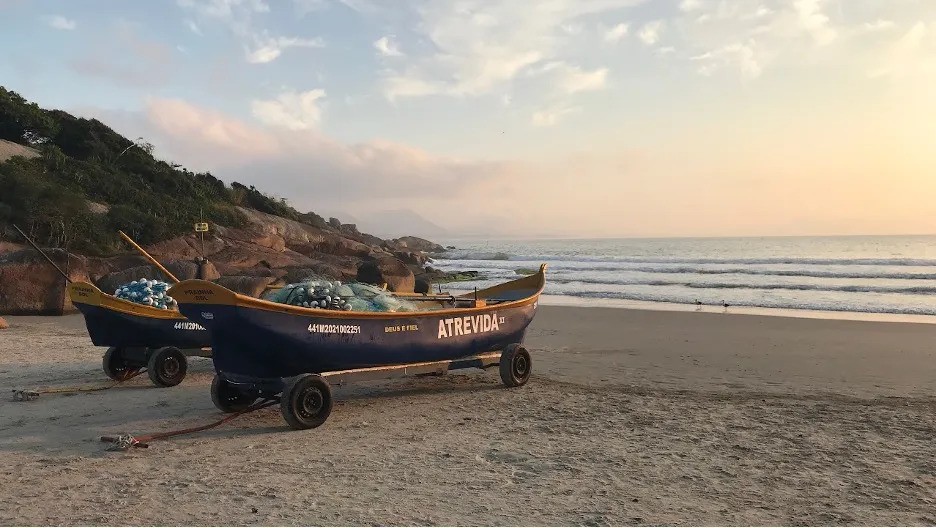 Two fishing boats sit on the sand of a Brazilian beach.